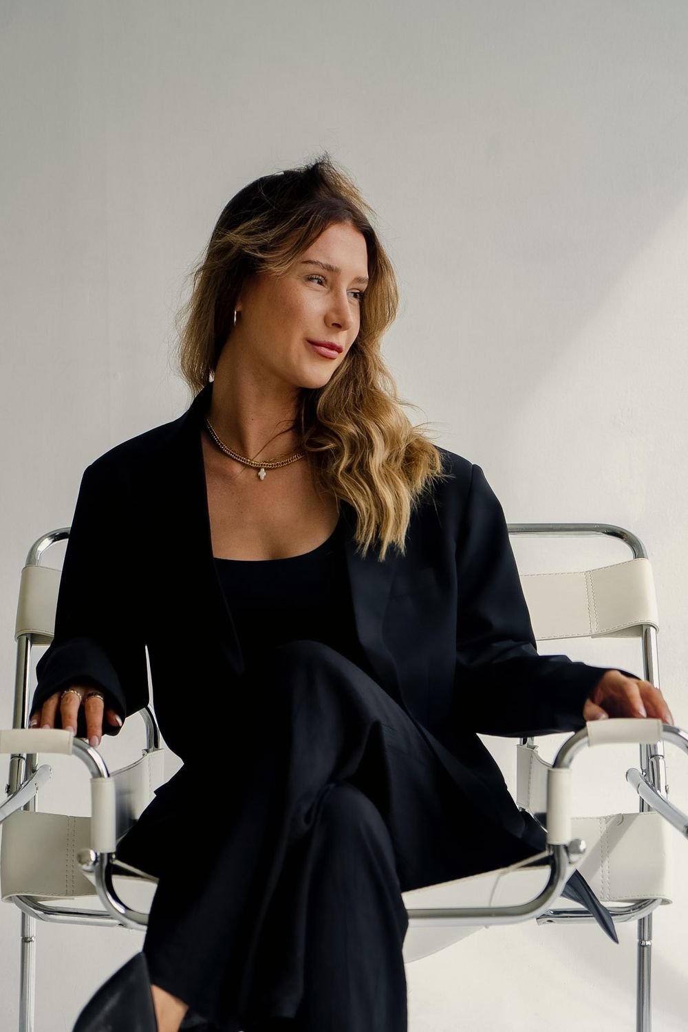 Liv Ball in a black suit, seated on a chrome and leather chair