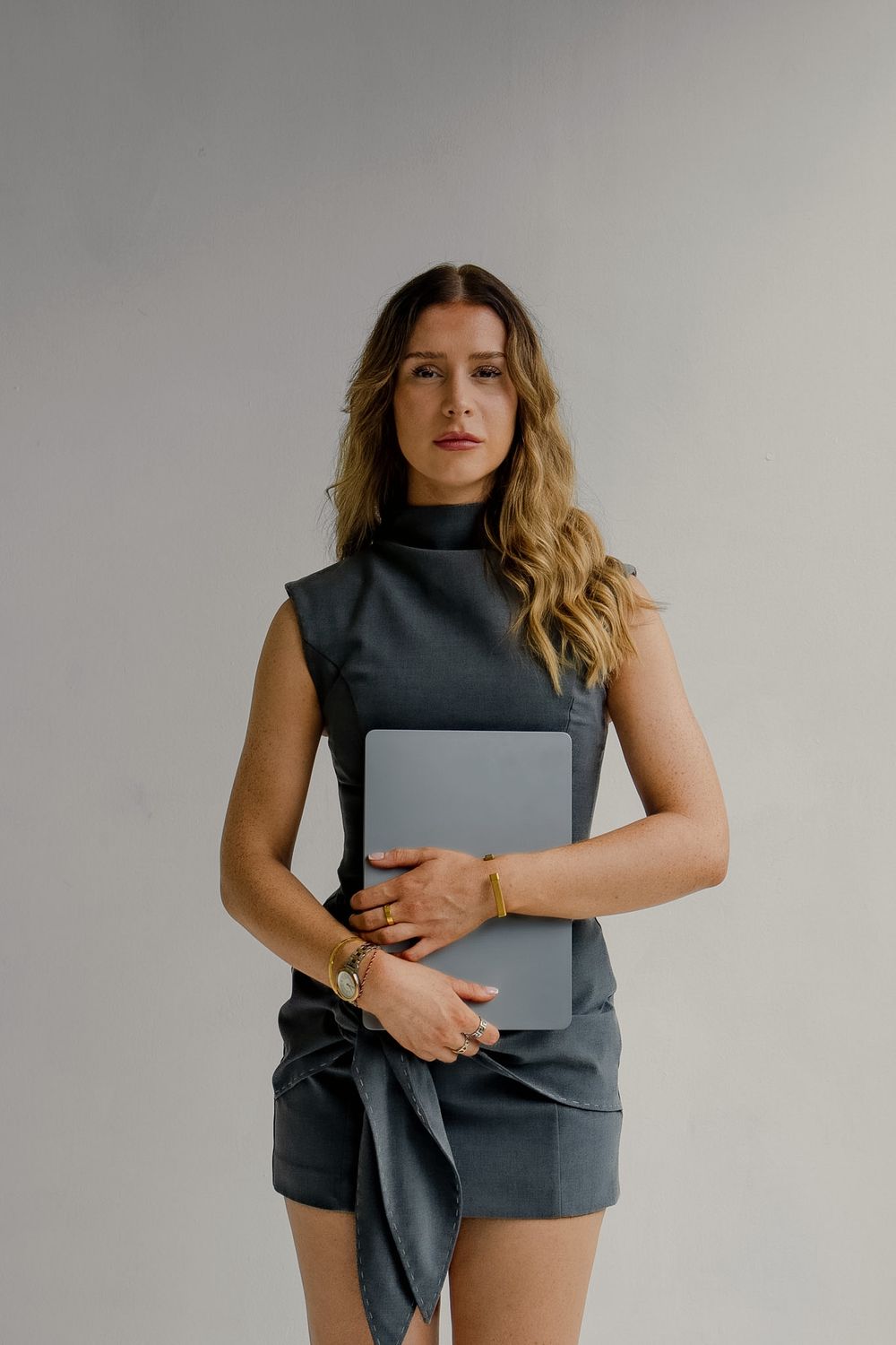 Liv Ball holding a laptop in a grey studio